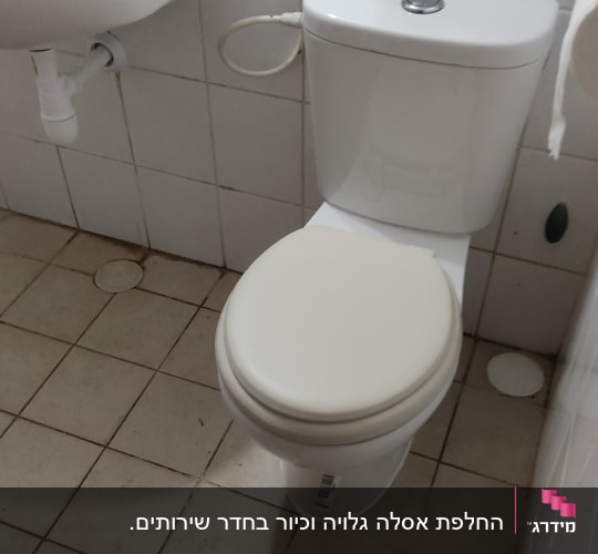 אסלה עם צינור מים ליד כיור בחדר אמבטיה